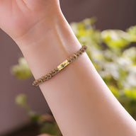 Bracelet femme en perles d’œil de tigre marron avec main égyptienne en métal doré.