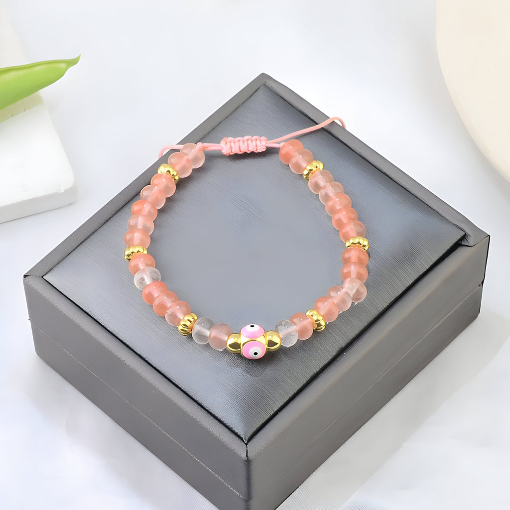 Bracelet femme en quartz rose avec petit œil coloré et perles dorées sur cordon rose ajustable.