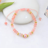 Bracelet ajustable en quartz rose avec perles dorées et petit œil rose au centre.