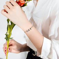 Bracelet argenté en acier inoxydable avec papillons délicats sur poignet féminin.