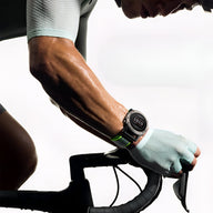 Bracelet en nylon noir avec attache velcro verte pour montre connectée Garmin, porté lors d'une activité cycliste.