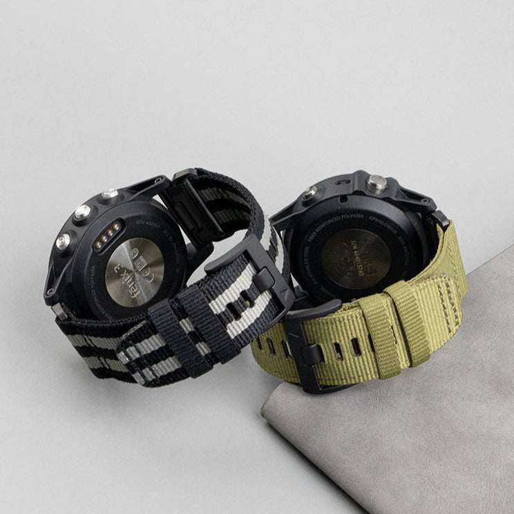 Bracelet nylon résistant noir et gris 26 mm compatible montre Garmin à fermoir métal et boucle ajustable, à côté d'un.