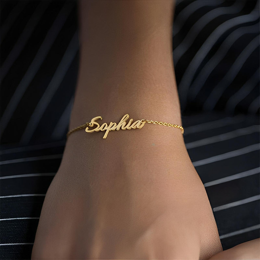 Bracelet prénom ajustable en acier inoxydable doré avec nom "Sophia" en lettres cursives fines.