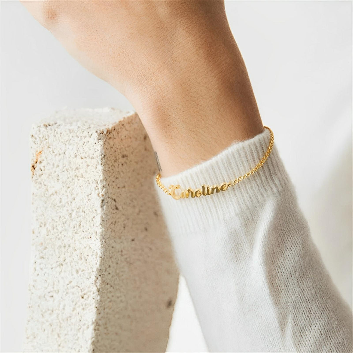 Bracelet prénom personnalisable en acier inoxydable doré, lettres en script, ajustable sur poignet féminin.