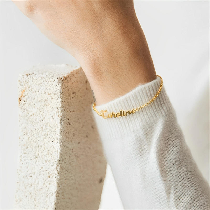 Bracelet prénom personnalisable en acier inoxydable doré, lettres en script, ajustable sur poignet féminin.