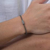 Bracelet prénom en acier inoxydable gris foncé avec maille vénitienne fine et fermoir sécurisé porté au poignet.