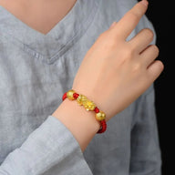 Bracelet rouge en fil ciré avec Pi Xiu doré porte-bonheur sur poignet, style tibétain.
