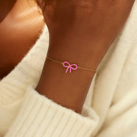 Bracelet fin en argent avec un ruban rose brillant délicat sur poignet peau foncée.