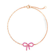 Bracelet fin en or rosé avec un pendentif nœud papillon orné de pierres roses lumineuses.