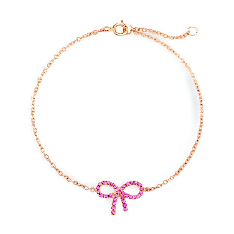 Bracelet fin en or rosé avec un pendentif nœud papillon orné de pierres roses lumineuses.