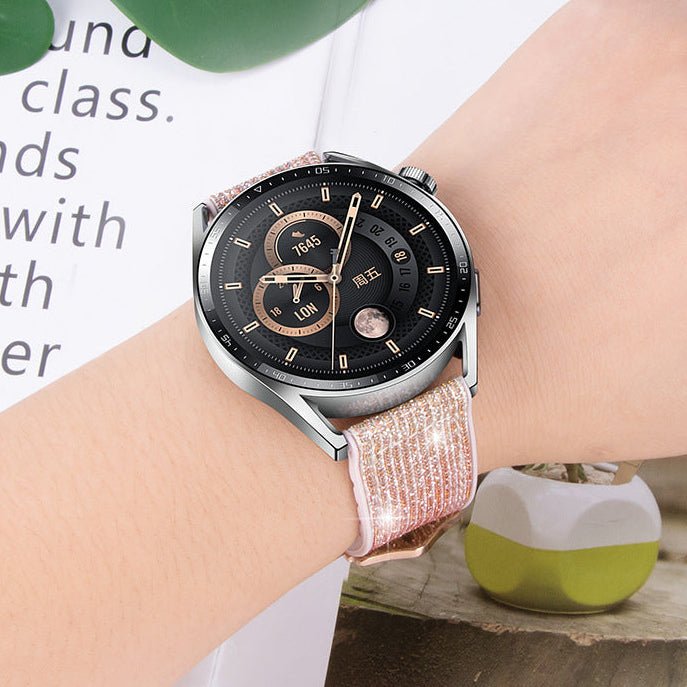 Bracelet scintillant rose en silicone doux avec boucle ardillon porté sur montre connectée argentée.