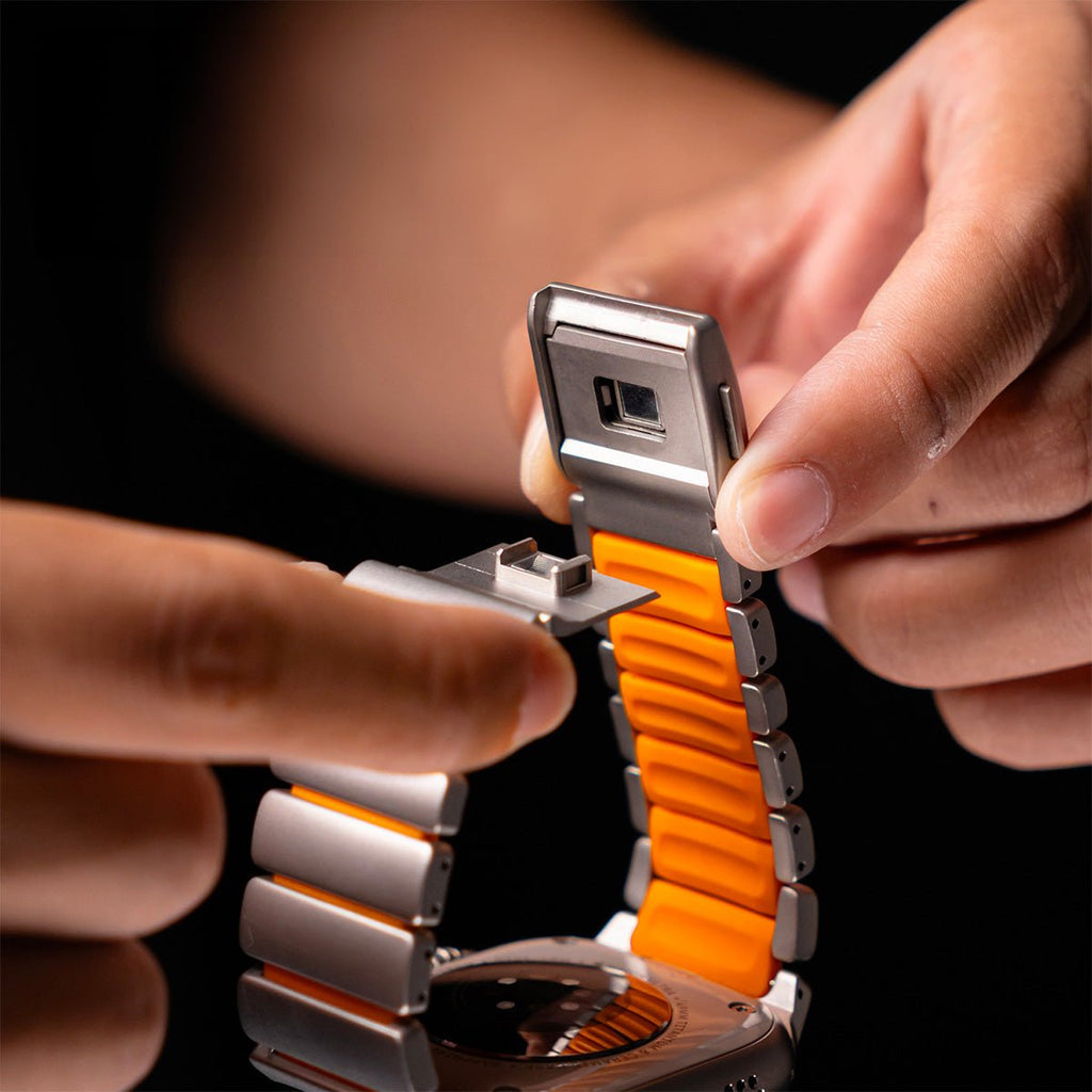 Bracelet Samsung Watch Ultra en titane gris avec intérieur silicone orange vif et maillons robustes, fixation magnétique.