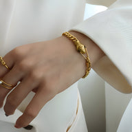 Bracelet serpent plaqué or 18 carats avec yeux verts, design élégant et fin sur poignet féminin.