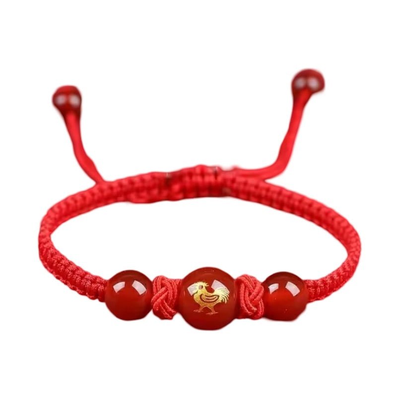 Bracelet en nylon fil rouge avec perles rouges et signe du zodiaque chinois doré au centre.