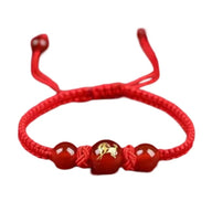 Bracelet en nylon rouge avec perles rouges et une perle centrale dorée gravée d'un signe du zodiaque chinois.