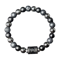 Bracelet élastique en perles noires de lave, hématite brillante et pendentif cylindrique gravé style signe zodiacal.