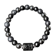 Bracelet élastique avec perles noires mates, perles de lave texturées et hématite brillante, cylindre noir gravé style.