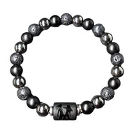 Bracelet élastique noir avec perles rondes de lave et hématite, motif signe astrologique gravé sur perle centrale en pierre.