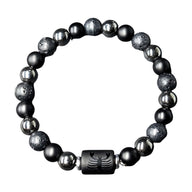 Bracelet élastique en perles rondes noires, lave volcanique et hématite grise, avec un fermoir noir gravé d’un symbole.