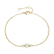 Bracelet fin en acier inoxydable doré avec perle centrale blanche et fermoir mousqueton.