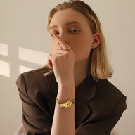 Bracelet femme en titane doré style boucle de ceinture, design Malena élégant et minimaliste.