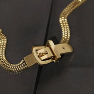 Bracelet femme en titane doré avec boucle de ceinture élégante et finition brillante.