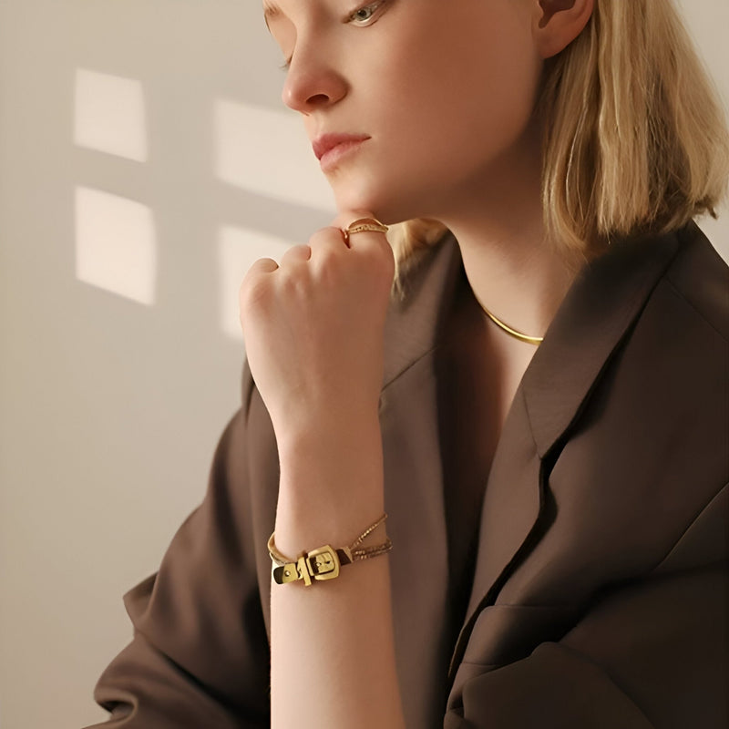 Bracelet boucle de ceinture en titane doré avec détails géométriques élégants porté au poignet féminin.