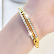 Bracelet fermeture éclair en titane doré avec chaînes et bords ornés de cristaux scintillants, pour femme.