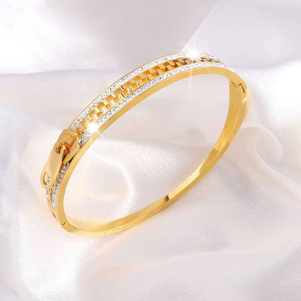 Bracelet en titane doré avec design fermeture éclair et incrustations de cristaux brillants.