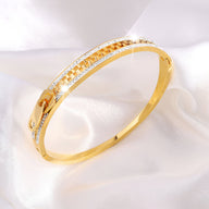 Bracelet en titane doré avec design fermeture éclair et incrustations de cristaux brillants.