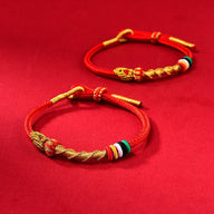Bracelet serpent en fil rouge ciré avec détails dorés et perles multicolores, style porte-bonheur.