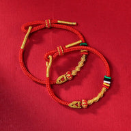 Bracelets serpent en fil rouge ciré avec détails dorés et petits drapeaux tricolores, style porte-bonheur.