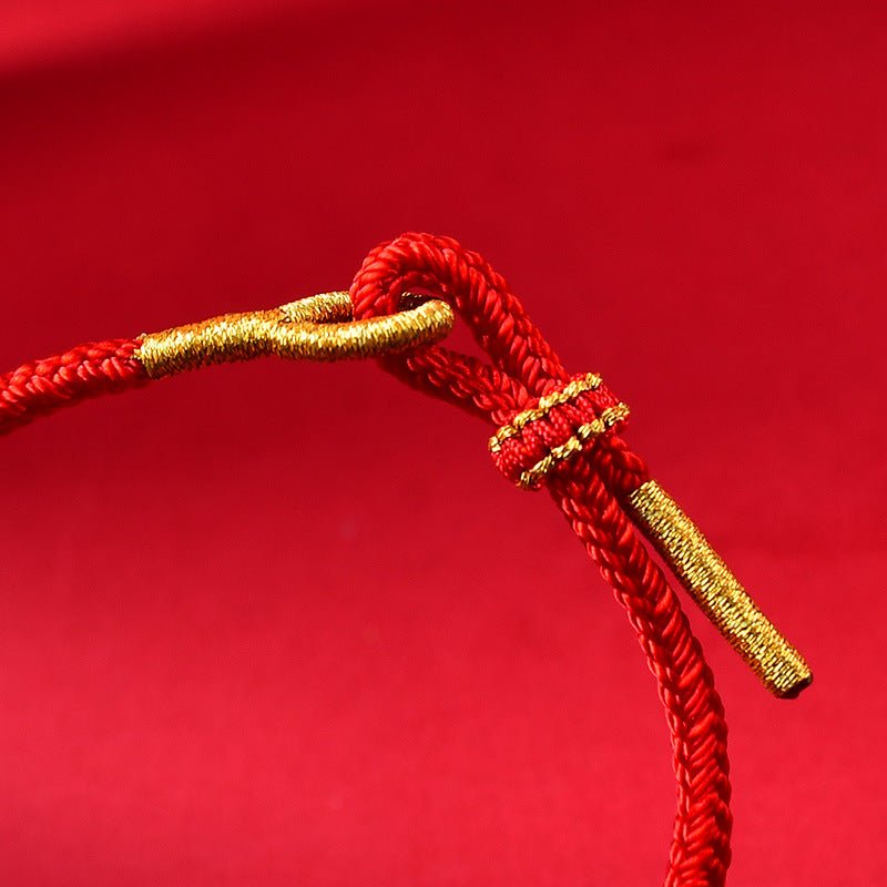 Bracelet rouge en fil ciré avec finitions dorées style serpent porte-bonheur.