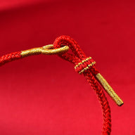 Bracelet rouge en fil ciré avec finitions dorées style serpent porte-bonheur.