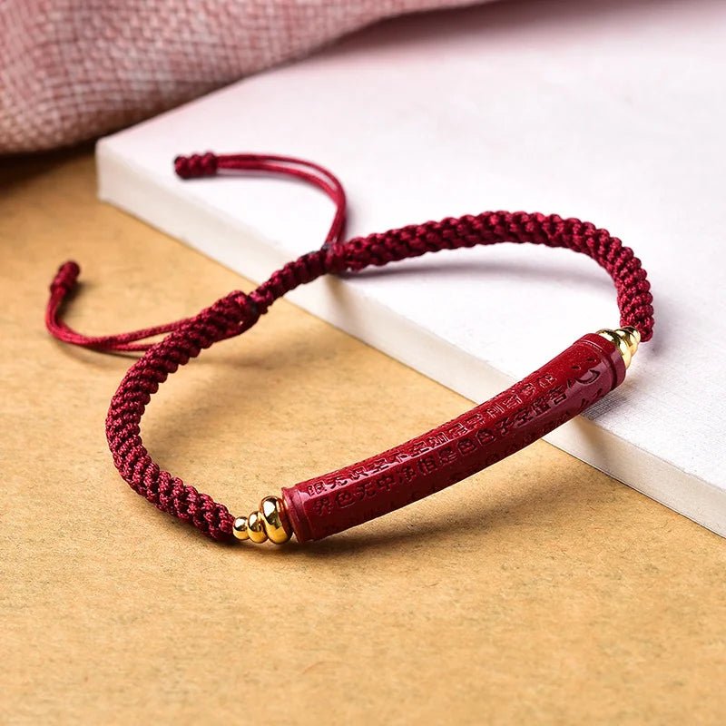 Bracelet rouge en fil ciré tressé avec barre centrale ornée de détails dorés, style unisexe.