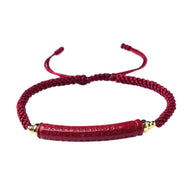 Bracelet rouge en fil ciré tressé avec barrelette texturée et détails dorés, modèle Sura.