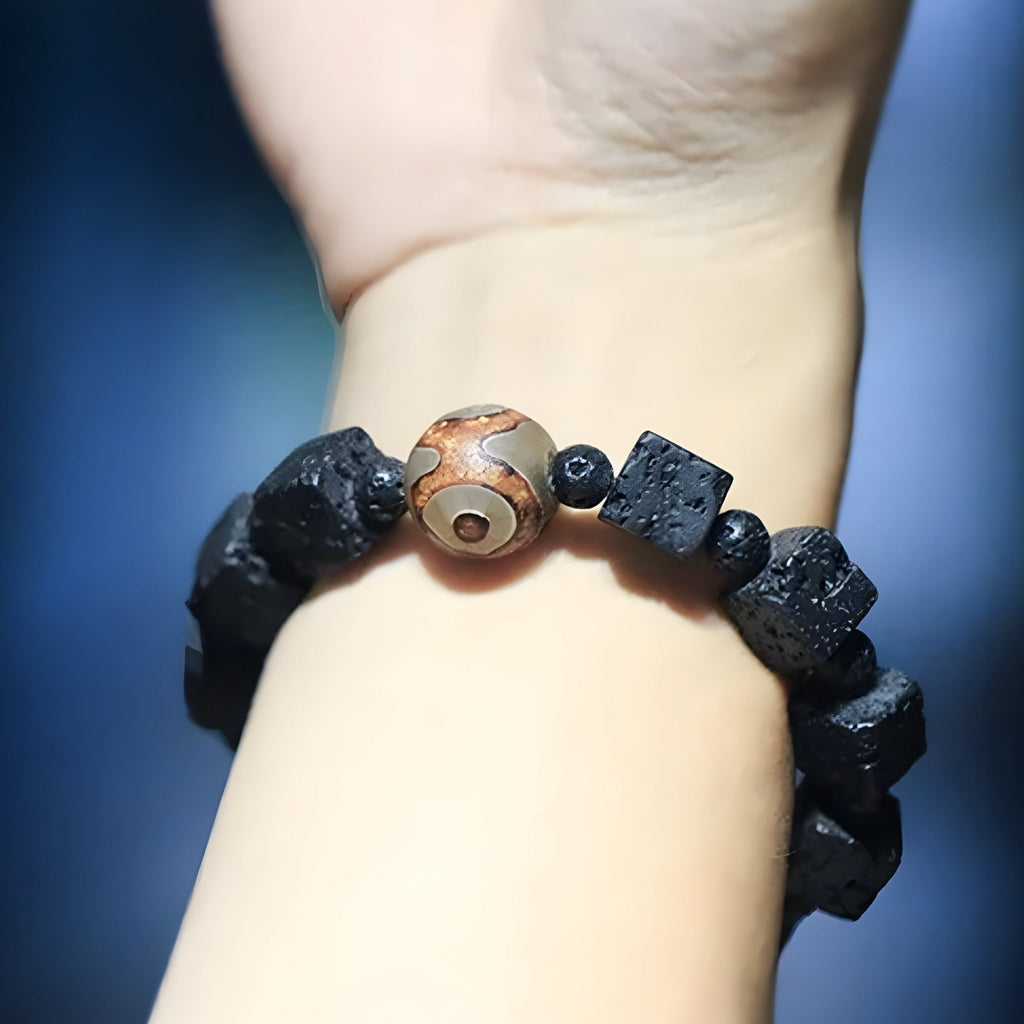Bracelet mixte avec pierres volcaniques cubiques noires et perle de Dzi marron aux motifs circulaires.
