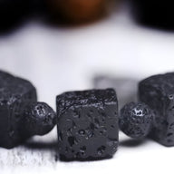 Bracelet mixte noir en pierres volcaniques cubiques et perle de Dzi noire texturée.