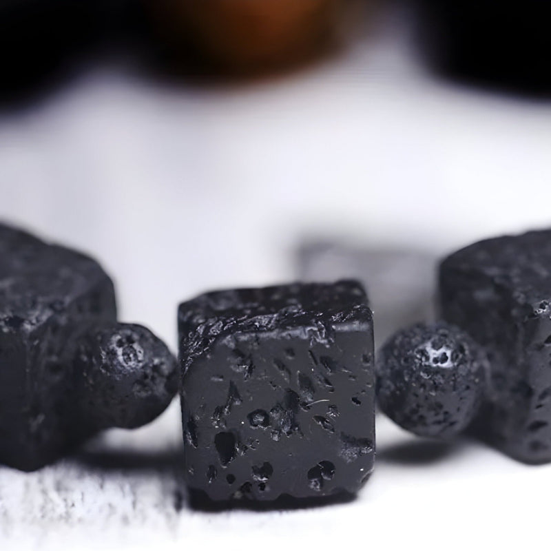 Bracelet mixte noir en pierres volcaniques cubiques et perle de Dzi noire texturée.