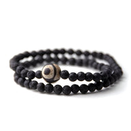 Bracelet tibétain double tour en pierres volcaniques noires avec perle de Dzi beige et noire centrale.