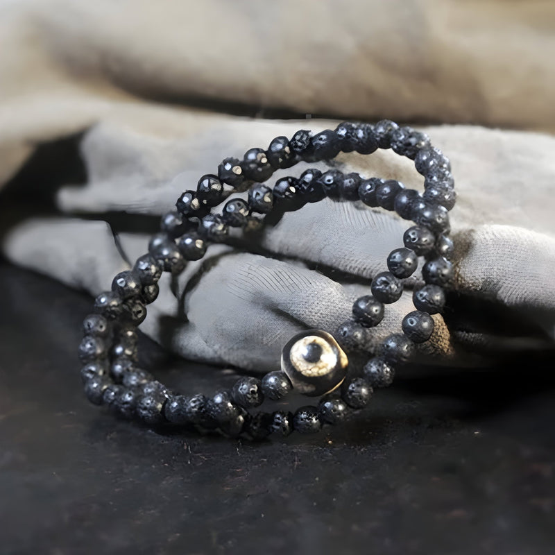 Bracelet tibétain noir en pierres volcaniques avec perle de Dzi argentée, style double tour.