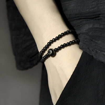 Bracelet double tour noir en pierres volcaniques avec perle de Dzi unique, style mixte élégant.