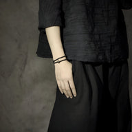 Bracelet tibétain noir en pierres volcaniques avec perle de Dzi, porté sur poignet.