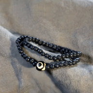 Bracelet noir en pierres volcaniques lisses avec perle centrale Dzi beige noire, style tibétain, mixte.