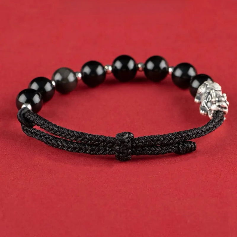 Bracelet tibétain en pierres noires d’obsidienne avec tête de Pi Xiu argentée et cordon noir tressé.