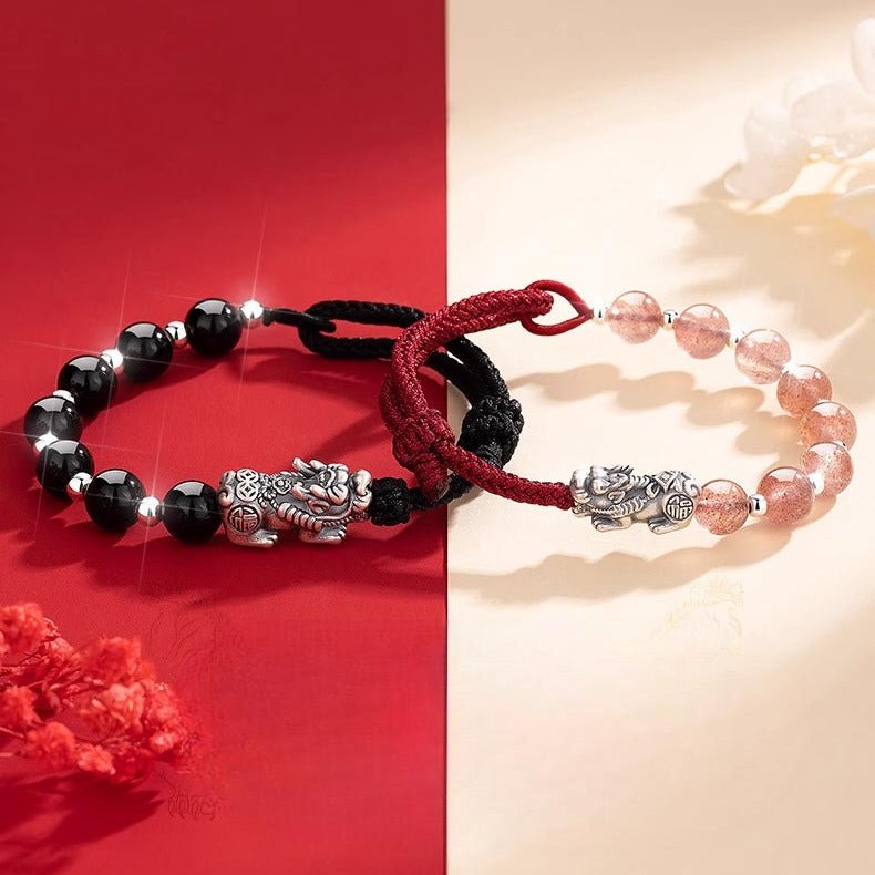 Bracelet tibétain duo en perles quartz rose et obsidienne avec charms Pi Xiu argentés et fil rouge ajustable.