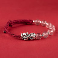 Bracelet tibétain en fil rouge avec perles de quartz rose et breloque Pi Xiu argentée.