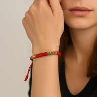 Bracelet tibétain en fil rouge avec détails tissés multicolores, style porte-bonheur.