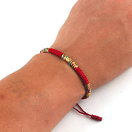 Bracelet tibétain en nylon rouge avec fils multicolores et fermeture ajustable, style porte-bonheur.