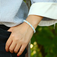 Bracelet tissé bi-colore bleu clair et blanc style mixte porté au poignet.